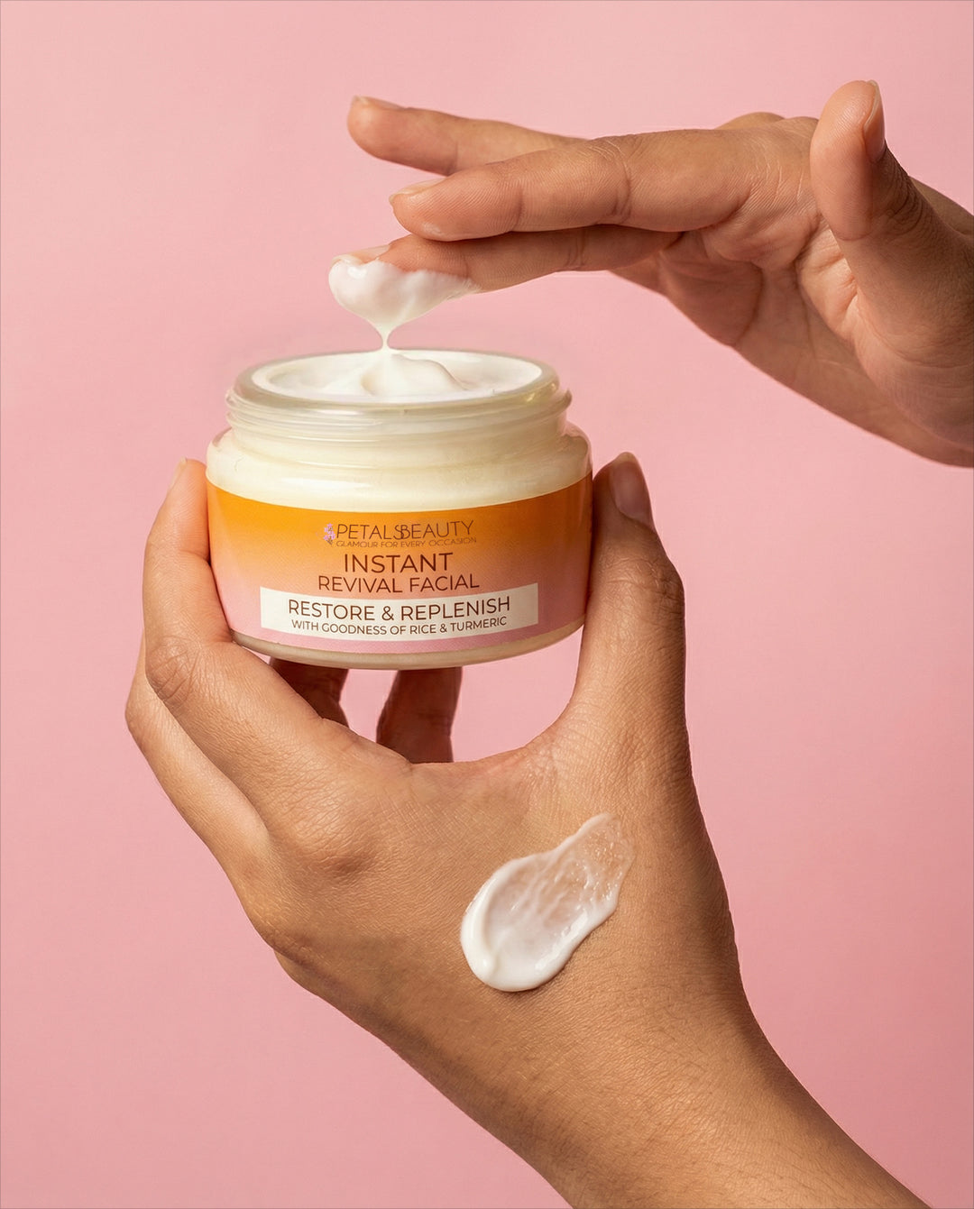 Hand applying cream from a 'Petal Beauty' jar against a pink background